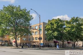 Chicago apartment for rent - A person is crossing the street in front of a building with a green awning.