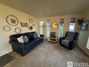 Anchorage apartment for rent - A living room with a black couch, a grey armchair, and a wall decorated with circular frames.