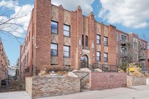 Denver apartment for rent - A red brick building with a black iron fence in front.