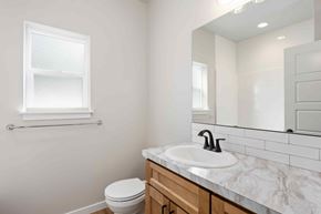 Twin Falls house for rent - A bathroom with a toilet, sink, and mirror.