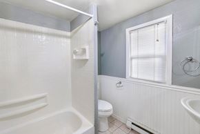Kimberly house for rent - A white bathroom with a toilet, tub, and window.