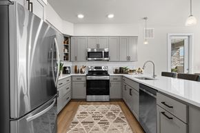 Phoenix apartment for rent - A modern kitchen with a stainless steel refrigerator and a patterned rug on the floor.