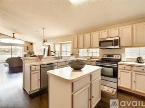 Orlando house for rent - A kitchen with white cabinets and appliances, a large island in the middle, and a dining area with a table and chairs.