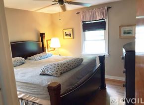 Fayetteville apartment for rent - A bedroom with a bed, a ceiling fan, and a window with a curtain.