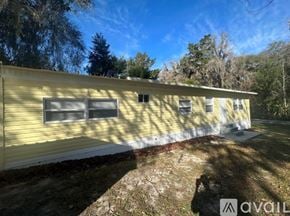Inverness apartment for rent - A yellow house with a white fence is surrounded by greenery.