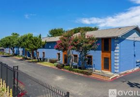 Dallas apartment for rent - A blue building with a brown door and windows is surrounded by a black fence.