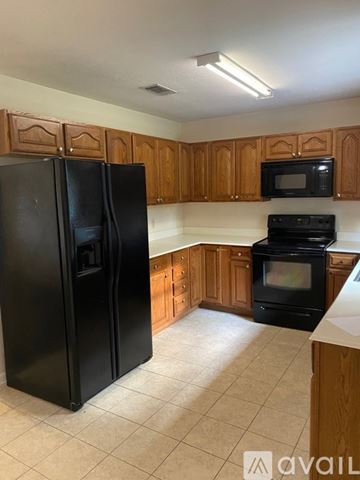 Deridder house for rent - A black refrigerator stands in a kitchen with wooden cabinets.