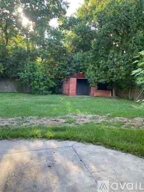 Deridder house for rent - A backyard with a red building and a concrete path.