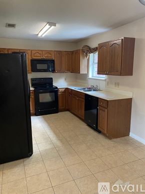 Deridder house for rent - A kitchen with black appliances and wooden cabinets.