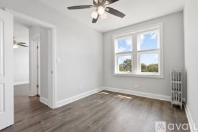 Chicago apartment for rent - A room with a ceiling fan and a window with a view of trees outside.
