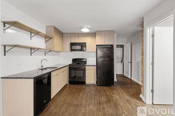 Chicago apartment for rent - A kitchen with black appliances and wooden floors.