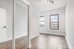 Chicago apartment for rent - A spacious room with a sliding door, wooden flooring, and a window with a view of bare trees outside.