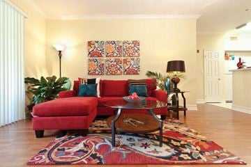 Miami Lakes apartment for rent - A living room with a red couch and a large tapestry hanging on the wall.