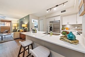 Miami Lakes apartment for rent - a kitchen with white counter tops and stools and a living room