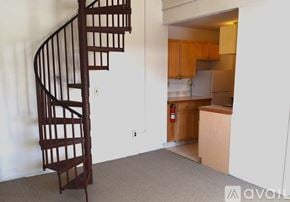 Poultney apartment for rent - A spiral staircase in a room with a kitchen in the background.