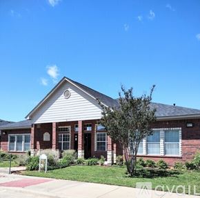 Gatesville apartment for rent - A red brick house with a white roof and a tree in front.