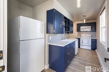 Butte apartment for rent - A kitchen with a white refrigerator and blue cabinets.