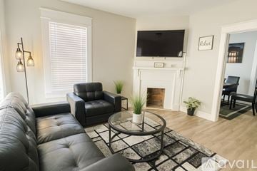 Greenville house for rent - A living room with a black leather couch and a fireplace.