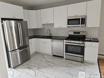 Jersey City apartment for rent - A kitchen with white cabinets and a black and white marble floor.