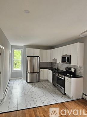 Jersey City apartment for rent - A kitchen with white cabinets and a black and white tiled floor.