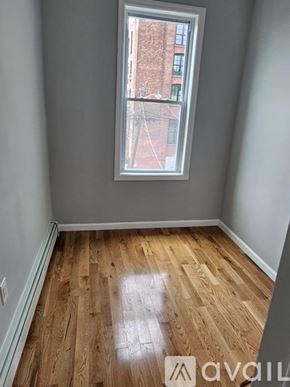 Jersey City apartment for rent - A room with wooden flooring and a window showing a red brick building outside.