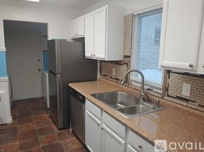 Anchorage house for rent - A kitchen with a sink, refrigerator, and cabinets.