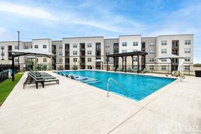 New Braunfels apartment for rent - A swimming pool is surrounded by lounge chairs in front of apartment buildings.