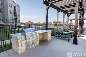 New Braunfels apartment for rent - A BBQ grill is on a stone block and there are green chairs around it.