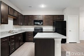 New Braunfels apartment for rent - A kitchen with dark brown cabinets and a black refrigerator.