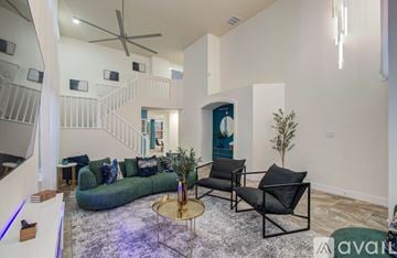 Spring house for rent - A living room with a green couch, a black chair, and a small table with a plant on it.