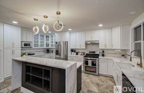 Spring house for rent - A modern kitchen with white cabinets and marble countertops.