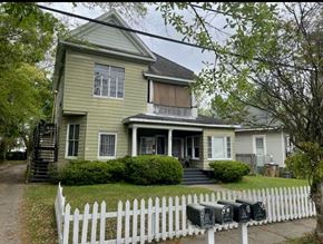 Mobile house for rent - A two-story house with a white picket fence in front.