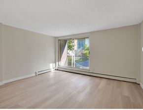 Calgary apartment for rent - Empty room with wooden flooring and a window overlooking a pool.