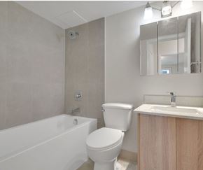 Calgary apartment for rent - A white toilet sits next to a white bathtub in a bathroom.