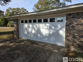Atmore house for rent - A house with a red roof and white trim is surrounded by a green lawn and trees.