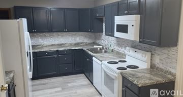 Atmore house for rent - A kitchen with black cabinets and a white stove top oven.