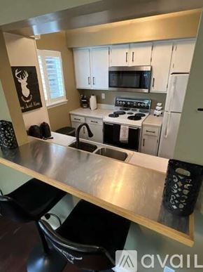Cody house for rent - A kitchen with white cabinets and a stove top oven.