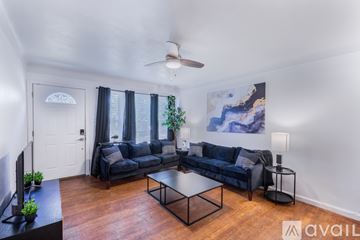 St. Louis house for rent - A living room with a black couch and a ceiling fan.