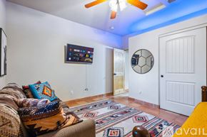 Lake Havasu City house for rent - A living room with a couch, a rug, a ceiling fan, and a TV mounted on the wall.