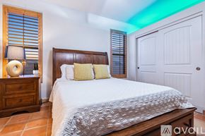 Lake Havasu City house for rent - A bedroom with a large bed, a wooden nightstand with a lamp, and a door.