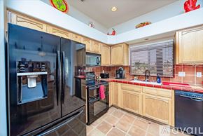 Lake Havasu City house for rent - A kitchen with a black refrigerator and wooden cabinets.