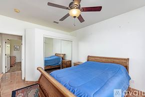 Lake Havasu City house for rent - A bedroom with a blue bedspread and a ceiling fan.