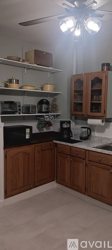 Pueblo house for rent - A kitchen with wooden cabinets and a ceiling fan.