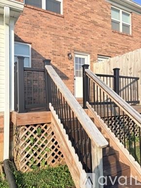 Bowling Green apartment for rent - A wooden staircase with a black railing leads up to a brick building.