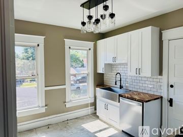 Racine apartment for rent - A kitchen with white cabinets and a black faucet.
