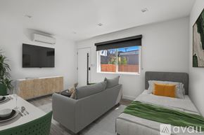 Los Angeles apartment for rent - A modern bedroom with a grey couch, a bed, and a television.