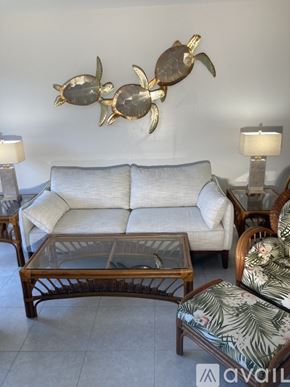 Jupiter condo for rent - A living room with a white couch, a wooden coffee table, and a wall decoration of three turtles.