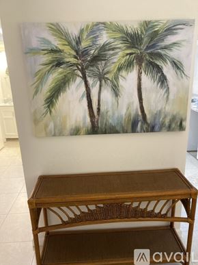 Jupiter condo for rent - A painting of two palm trees hangs on a wall above a wooden table.