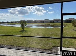 Port Charlotte house for rent - A view from a balcony looking out at a grassy field with a pond and houses in the distance.