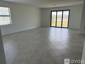 Port Charlotte house for rent - A spacious room with tiled flooring and a view of a grassy area through the sliding glass door.
